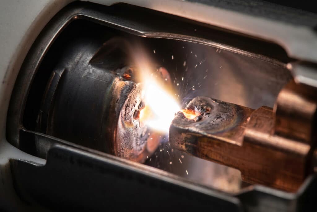 高故障電流遮断中の真空遮断器の分離した銅-クロム接点間の鮮やかな金属蒸気アークプラズマ柱の詳細なマクロ写真。.